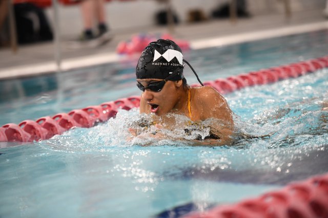 A young girl in a black swim cap racing in the National Swim Gala