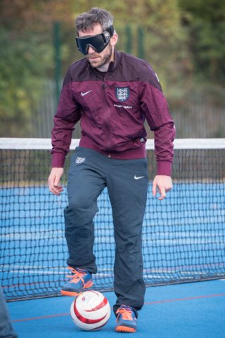 A man playing blind football wearing eye shades.