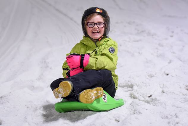 A young girl enjoying snowboarding at a dry ski slope.