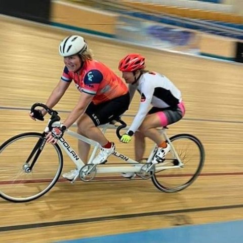 Diana tandem cycling with her pilot around a race track.